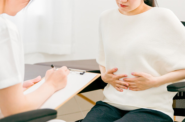 腹痛で悩む患者が受診する様子